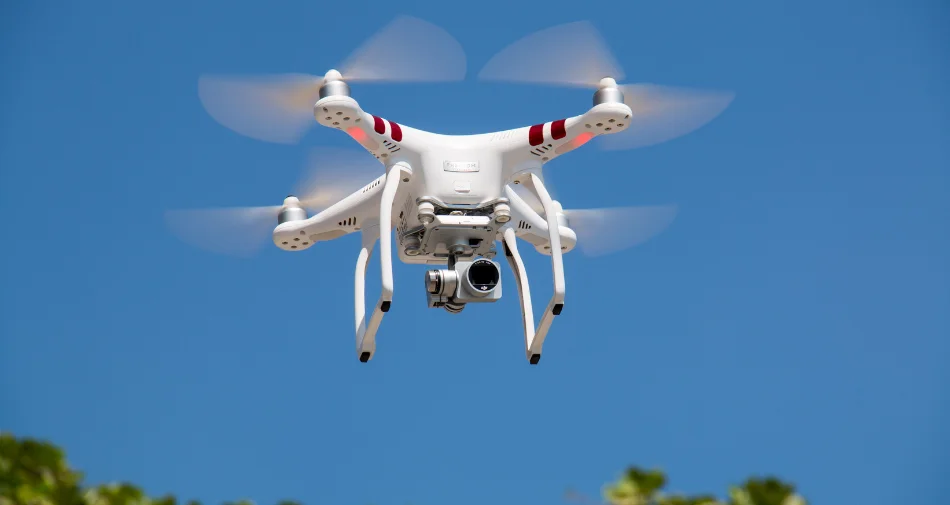 Biały dron podczas lotu na tle niebieskiego nieba